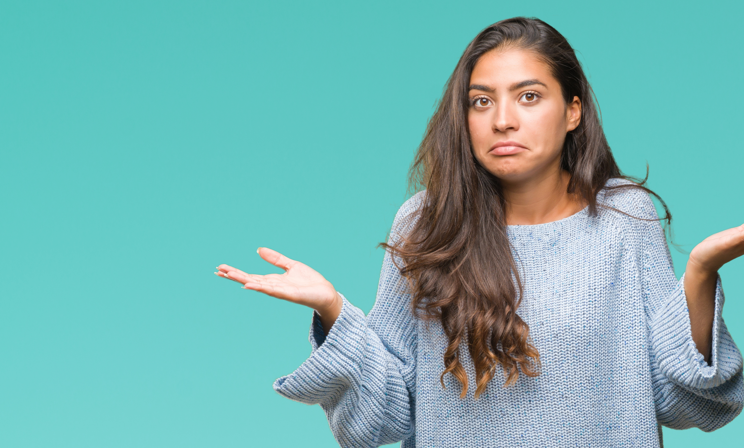 Young beautiful arab woman wearing winter sweater over isolated background clueless and confused expression with arms and hands raised. Doubt concept.