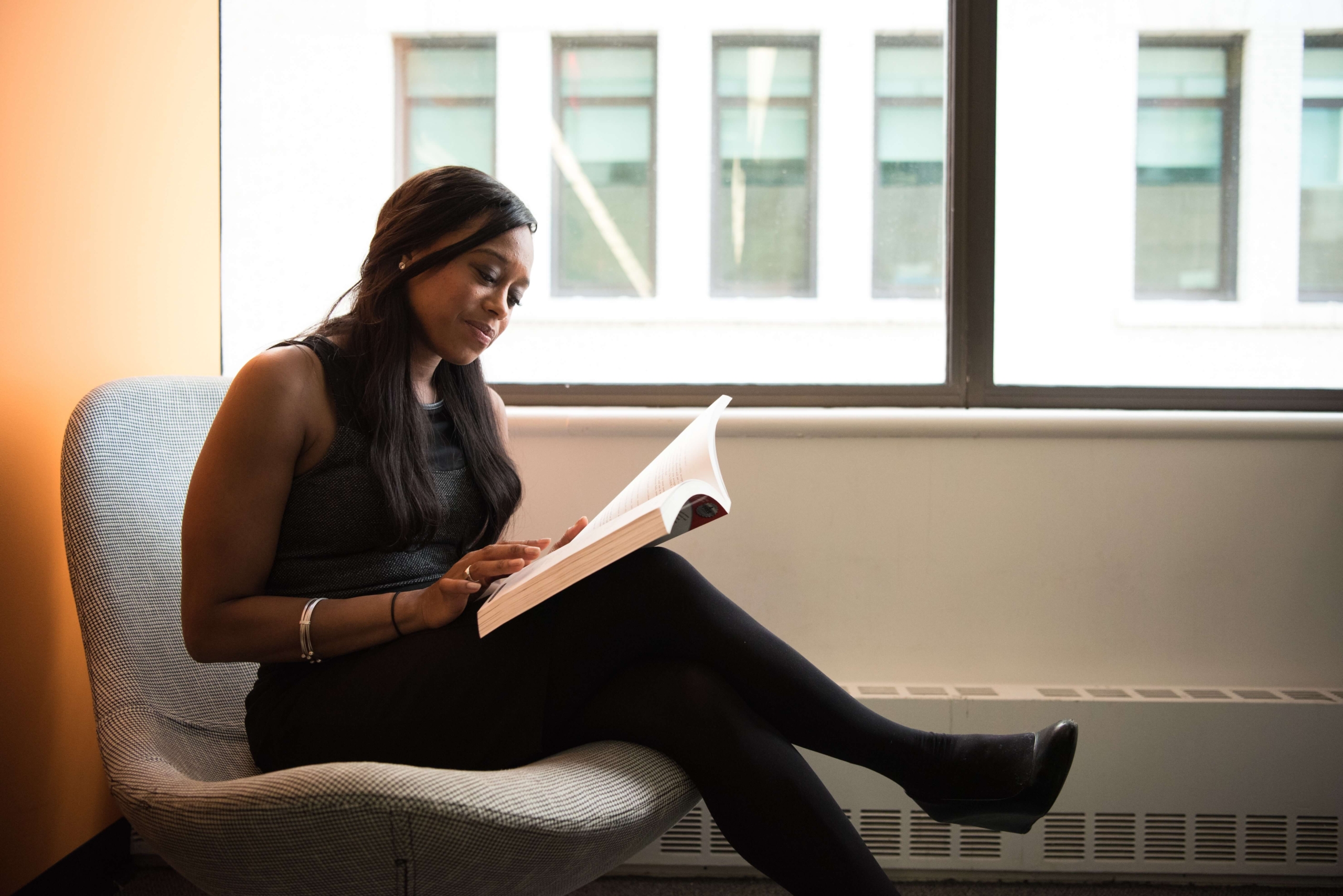 Woman Sitting in Chair Reading Book