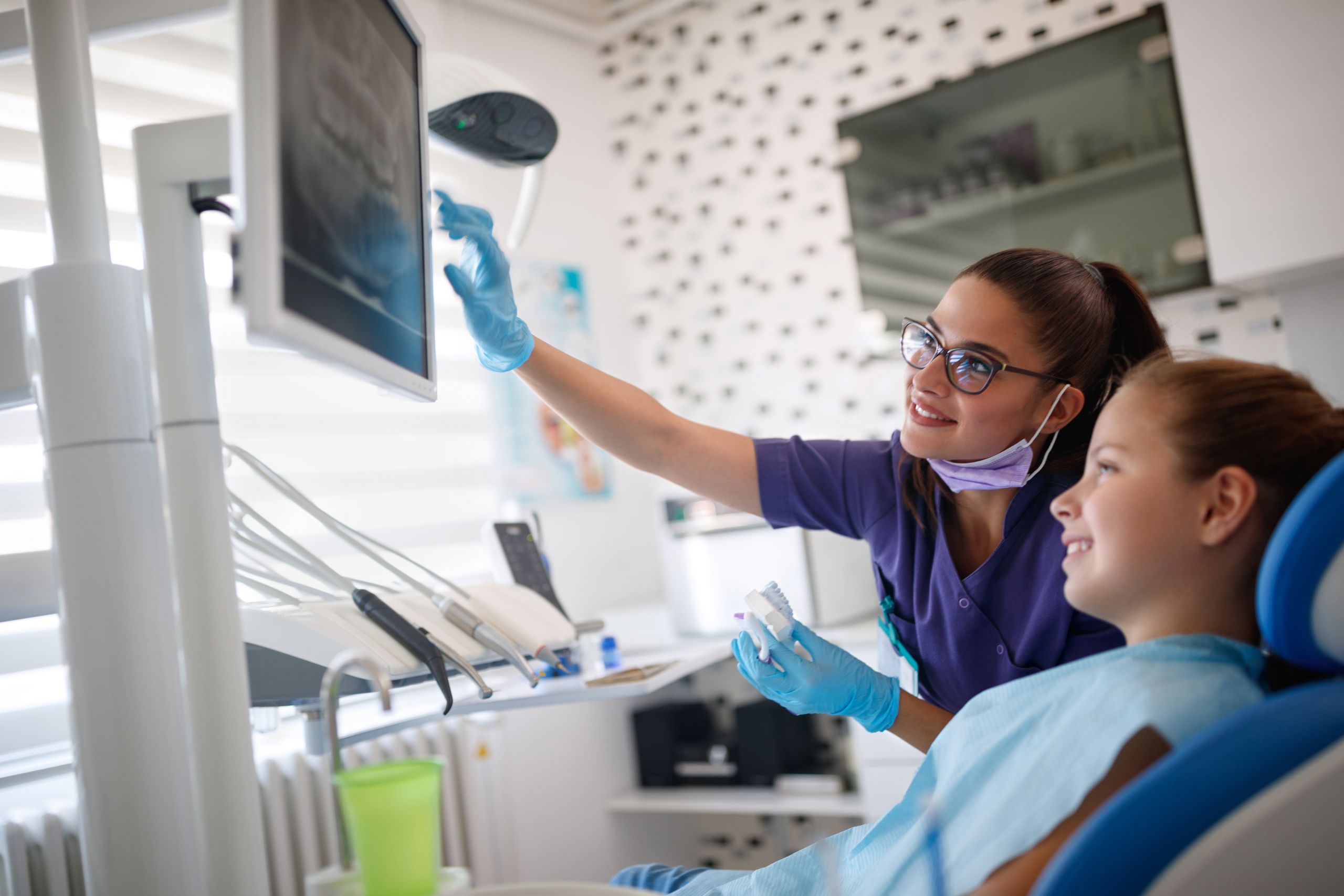 Dentist with female young patient looking at her dental x-ray